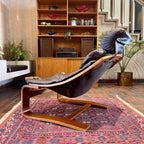 Side view of Kroken lounge chair showing reclined leather seat and sculptural teak frame