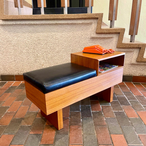 Teak Phone Bench / gossip bench Made in Canada black leather seat with orange phone sitting on top of open storage space 