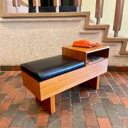Teak Phone Bench / gossip bench Made in Canada black leather seat with orange phone sitting on top of open storage space 