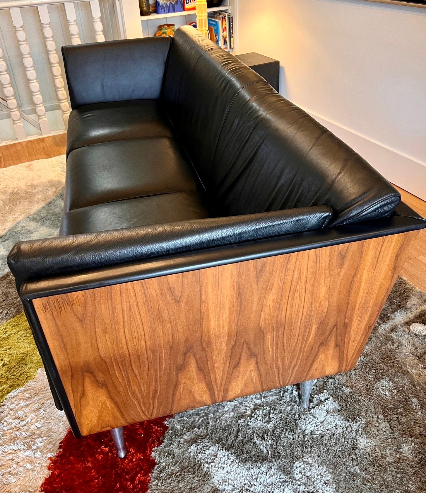 Side view of walnut wrapped Herman Miller sofa showing curved wood exterior and tapered aluminum legs