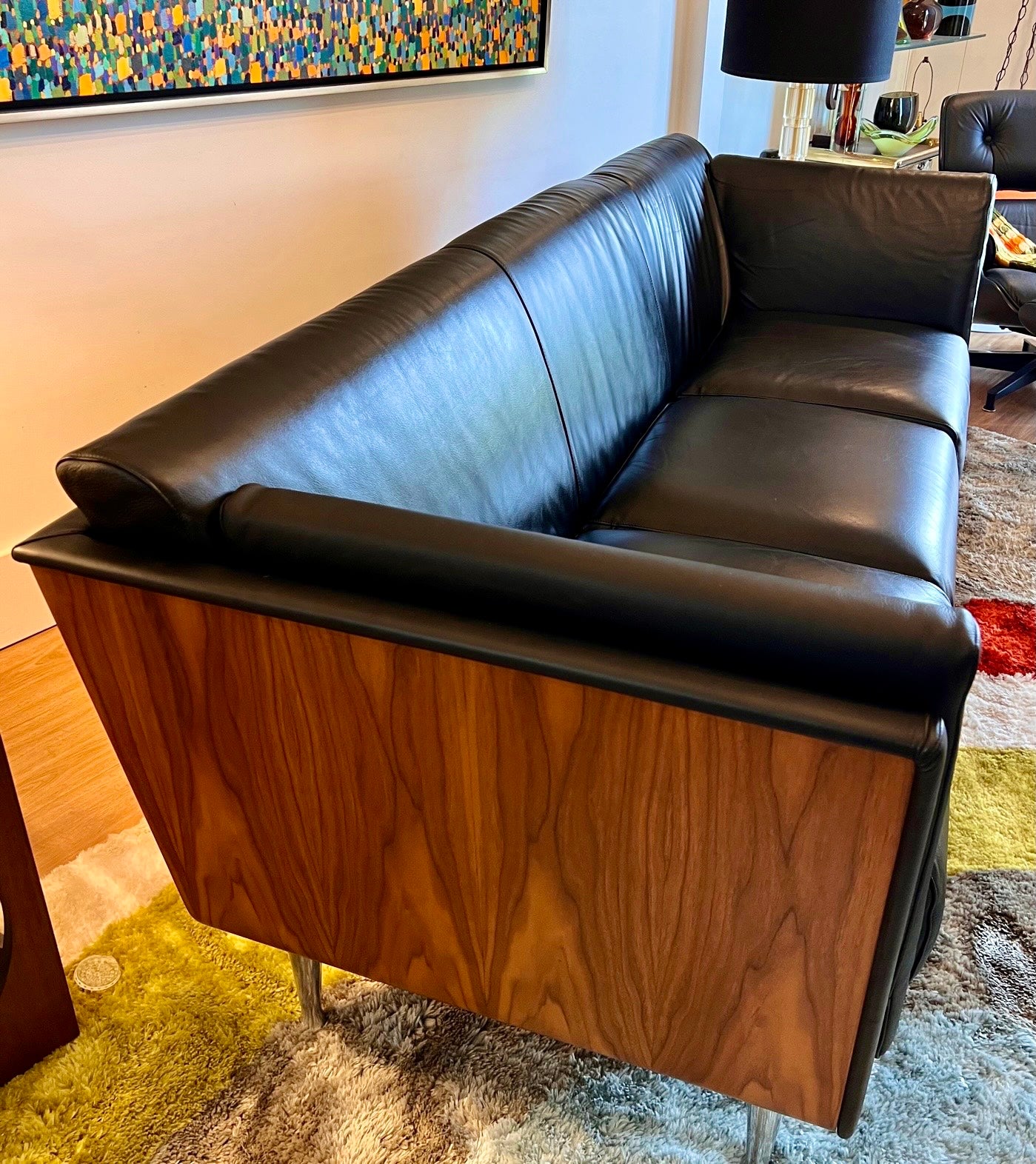 Angled view of Mark Goetz sofa showing walnut outer shell and black leather upholstery